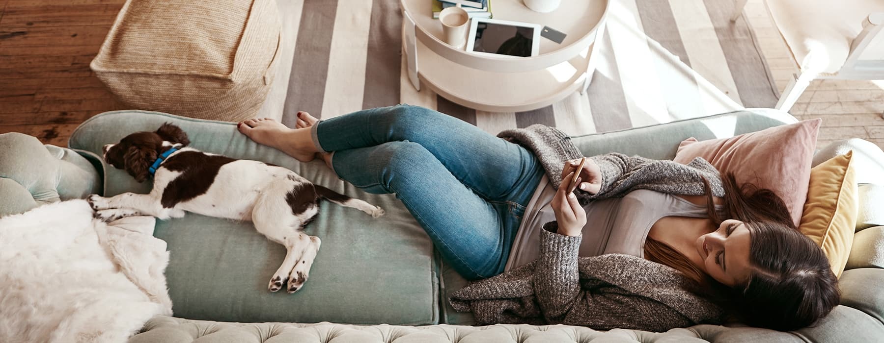 lifestyle image of a woman laying on a couch beside her pet
